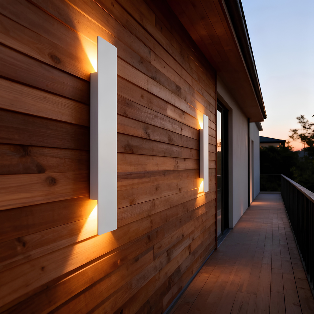 Matte black IP65 up/down wall pillar lights casting a warm ambient glow on a cedar timber exterior wall at dusk.
