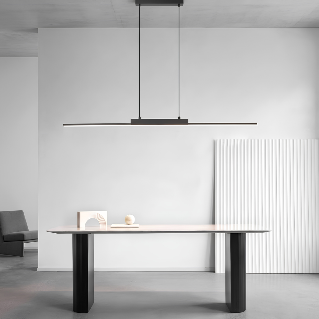Matte black linear LED pendant light suspended above a minimalist study desk styled with sculptural white ornaments, demonstrating versatile room placement.