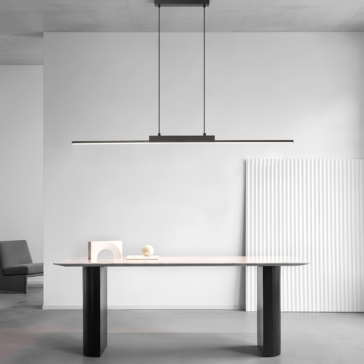 Matte black linear LED pendant light suspended above a minimalist study desk styled with sculptural white ornaments, demonstrating versatile room placement.