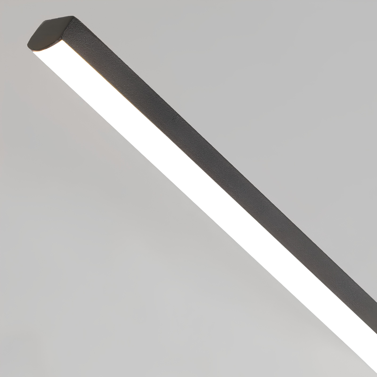 Close-up macro shot of a matte black aluminium linear pendant light showing the frosted acrylic diffuser and precise extrusion edge.