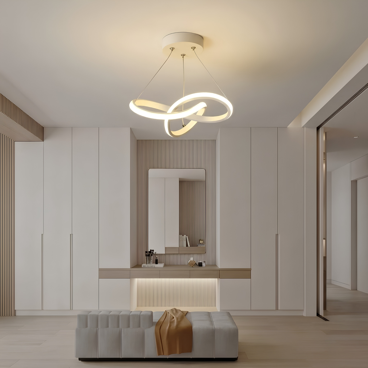 White sculptural interlocking-ring LED pendant light illuminated above a dressing table in a cloakroom, with a supplier caption overlay.