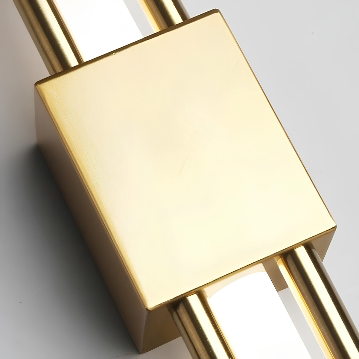 Close-up macro shot of the brushed brass junction block and frosted acrylic diffuser rods of a cylindrical up-down wall sconce.