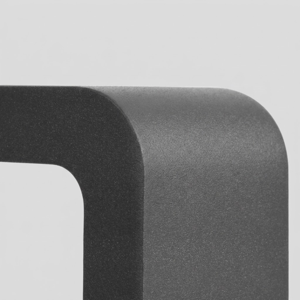 Close-up macro shot of the matte black powder-coated aluminium corner of an LED pathway bollard light, showing its fine-grain texture.
